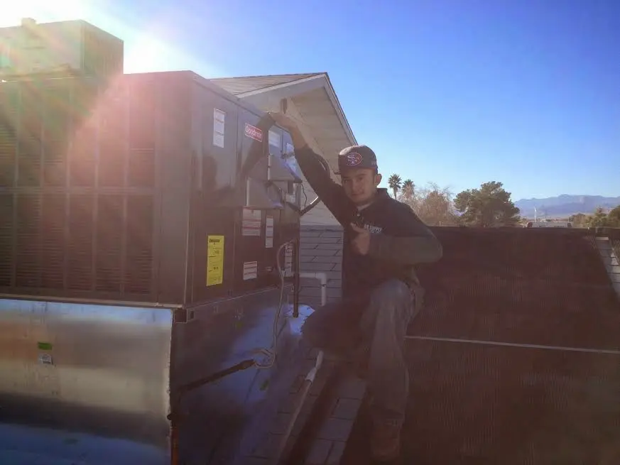 HVAC technician performing Air Duct Cleaning on a rooftop unit in Weatherford